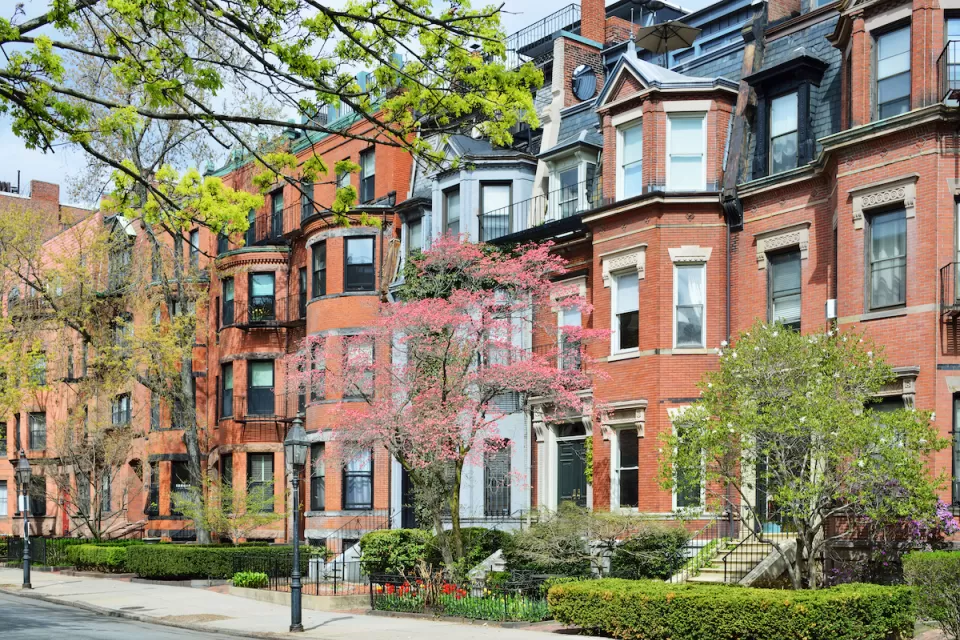 Brick brownstone homes in Back Bay, Boston with green hedges in front.